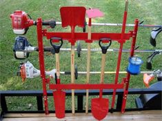 a red tool rack with shovels and other tools