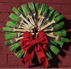 a wreath made out of bamboo sticks and red ribbon on top of a brick wall