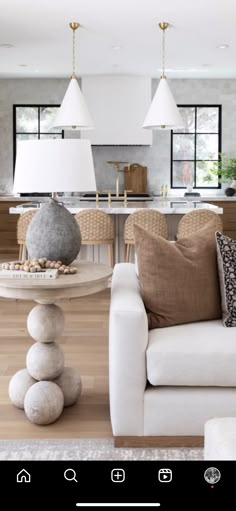 a living room filled with white furniture and lots of windows next to a kitchen area