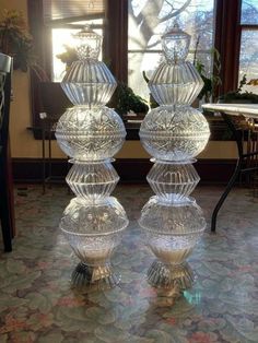 two clear glass vases sitting on top of a table in front of a window