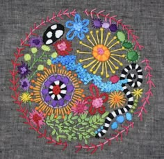 an embroidered design with flowers and bugs on it's side, in the middle of a circle