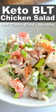 chicken salad with lettuce and tomatoes in a white bowl on top of a table