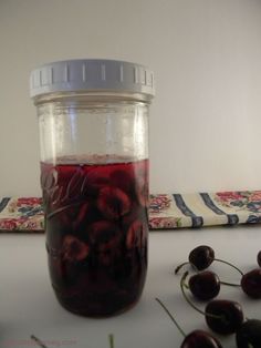 a jar filled with cherries sitting on top of a table