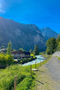 a road that is next to a river and some mountains in the background with houses on either side