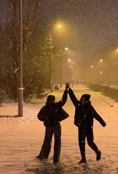 two people are standing in the snow holding their hands up and making a high five