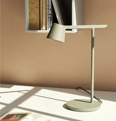 a white desk lamp sitting on top of a table next to a bookshelf