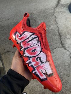 someone is holding up a red nike air max with graffiti on the side and bottom