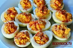 deviled eggs on a white plate with red chili sprinkled on the top