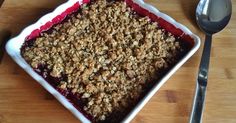 a square dish filled with crumbled oatmeal on top of a wooden table