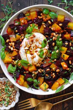 a white bowl filled with beets, carrots and chickpeas on top of a wooden table