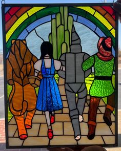 a stained glass window with three people walking down the street in front of a building