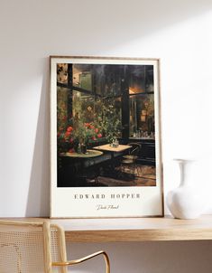 a table with chairs and vase on top of it next to a wall mounted poster