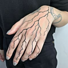 a person with tattoos on their arms and hands, holding onto a hand that has lightning drawn on it