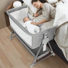 a woman laying in bed next to a baby on it's side with a pillow