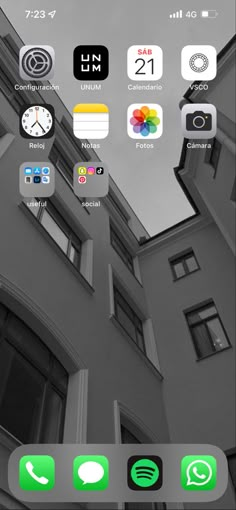 an iphone with different icons on the screen and in front of a building that appears to be black and white