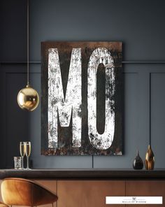 an old metal sign that says mo hangs on the wall next to a chair and lamp