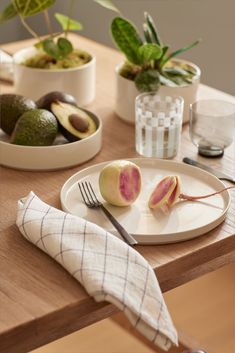 an avocado cut in half sitting on a plate with a fork and knife