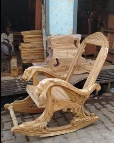 a wooden rocking chair sitting in front of a pile of wood planks on the ground