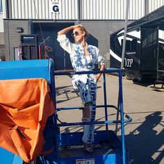 a woman standing on the back of a blue truck in front of a storage area