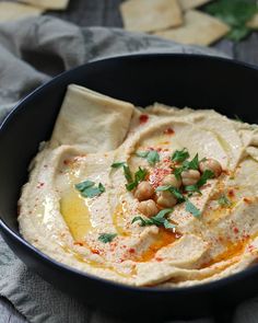 hummus in a black bowl with garnishes on top