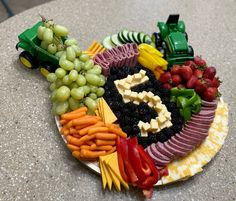 a platter with grapes, carrots, strawberries, and other fruits on it