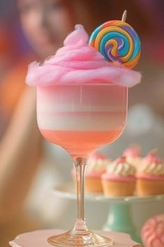 there is a cupcake in the glass with candy on top and a lollipop