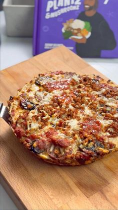 a pizza sitting on top of a wooden cutting board next to a purple children's book