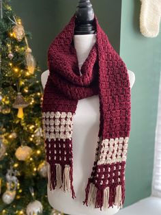 a red and white scarf sitting on top of a mannequin next to a christmas tree