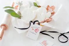 a bouquet of white flowers on top of a table next to some tags and a pen