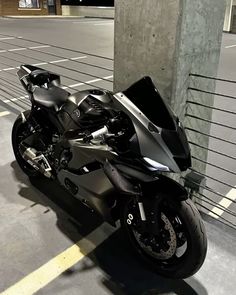 a black motorcycle parked on the side of a road next to a tall building in an empty parking lot