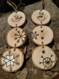 four wood slices with snowflakes and faces on them hanging from twine strings