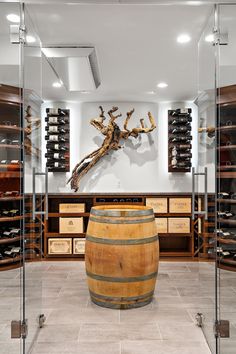 a large wooden barrel sitting in the middle of a room with wine bottles on shelves