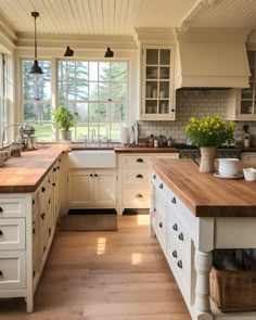 a kitchen with white cabinets and wooden counter tops in front of a large open window