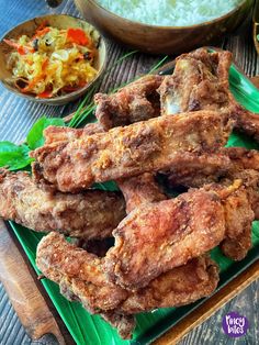 some fried food on a green plate with rice and other foods in bowls behind it