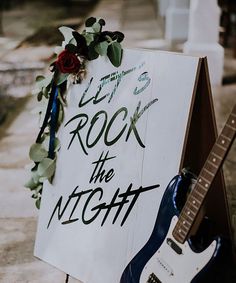 a sign that says rock the night next to a guitar