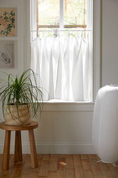 a potted plant sitting on top of a wooden stool in front of a window