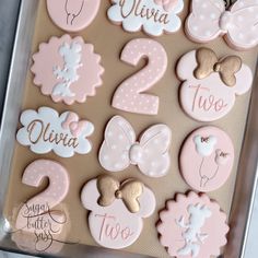 a box filled with lots of pink and white decorated cookies on top of a table