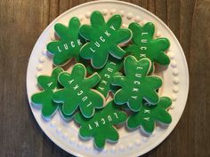 green shamrock cookies on a white plate with the words luck and luck written on them