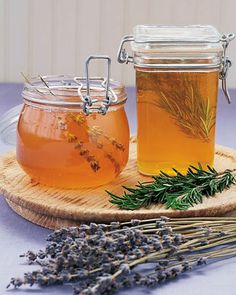 two jars filled with honey sitting on top of a wooden tray next to lavender flowers