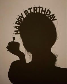 the silhouette of a woman holding a cup with candles in her hair and writing happy birthday on it