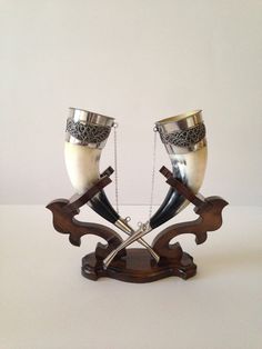 two silver vases with chains attached to them sitting on a white table next to each other