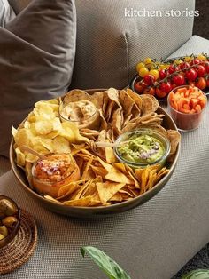 a bowl filled with chips and salsa next to bowls of fruit, vegetables and dips