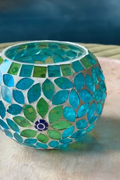 a blue and green vase sitting on top of a wooden table next to a wall