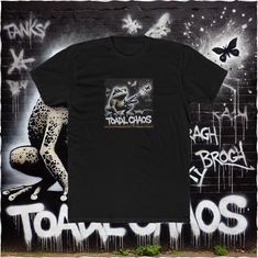 a black t - shirt sitting on top of a graffiti covered wall next to a cheetah