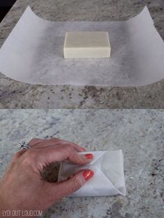 a hand holding a piece of wax on top of a counter next to a paper towel