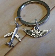 a metal keychain with an airplane and pilot's name on the front