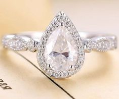 an engagement ring with a pear shaped diamond in the center and pave diamonds around it