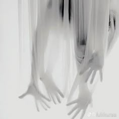 two hands reaching out from behind curtains to touch each other