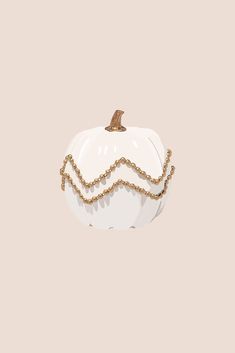 a white pumpkin with gold chains hanging from it's side on a beige background