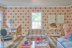 a living room filled with furniture and wallpaper covered in pink and blue patterns on the walls